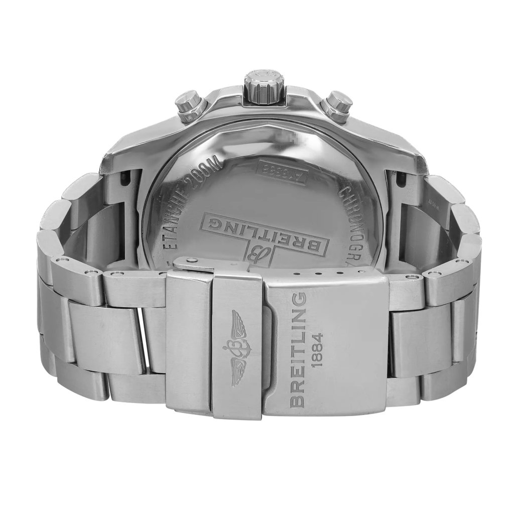 An image of a pre-owned wristwatch, showcasing the back view with a focus on the closed clasp. The watch is positioned upright, with the camera angle capturing it from a slightly elevated, close-up perspective. The metallic bracelet and clasp prominently display engraved branding details.