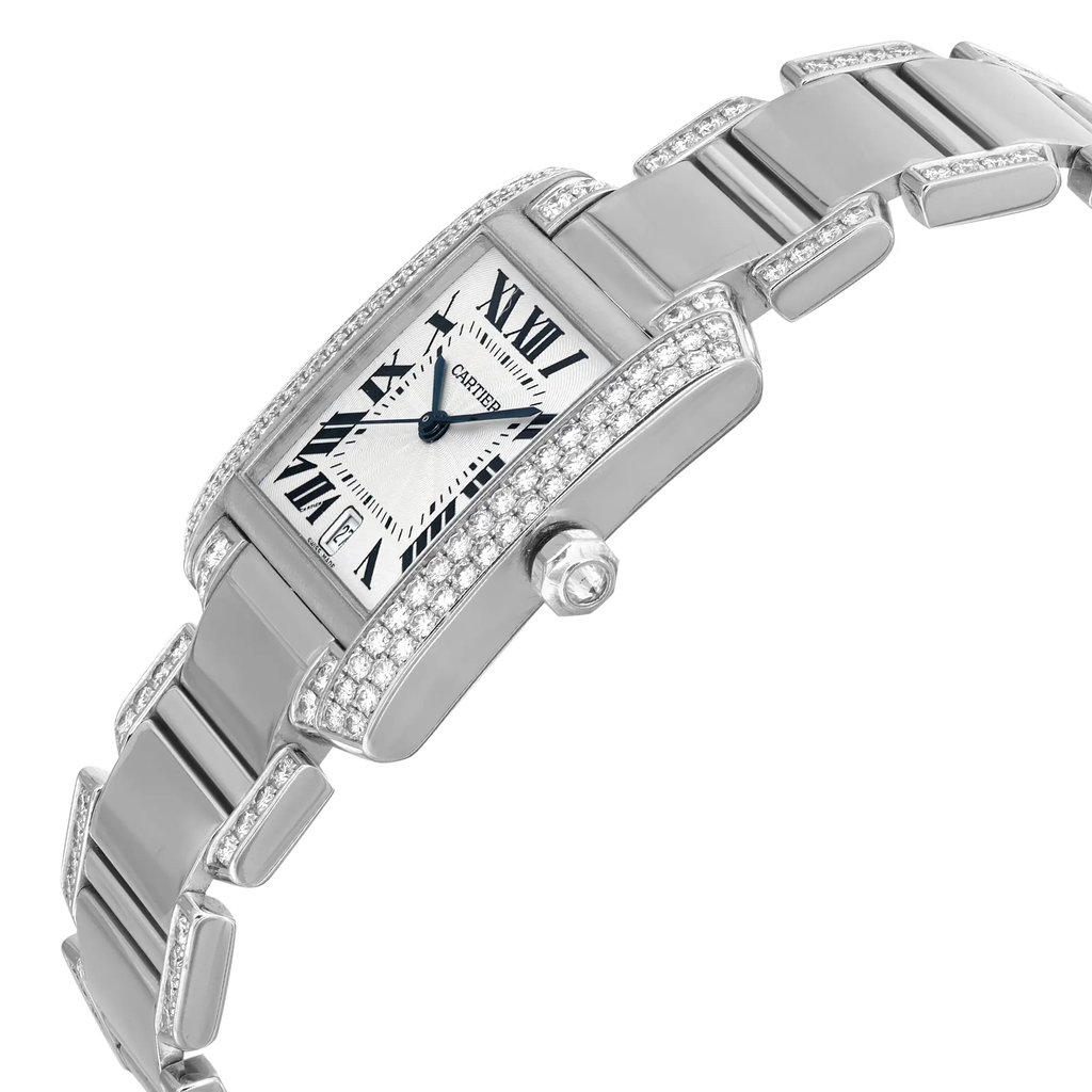 An image of a pre-owned Cartier luxury wristwatch, displayed in a side profile view with the crown visible. The watch has a rectangle shape and is constructed from white gold for both the band and case. It features a silver dial with a white gold bezel, Roman numerals, and a date indicator. The watch is adorned with sparkling diamonds along the edges and on the band, giving it an elegant appearance. The photo is taken at a close distance, emphasizing the watch's details and craftsmanship. Can have minor blemishes during handling and shipping.