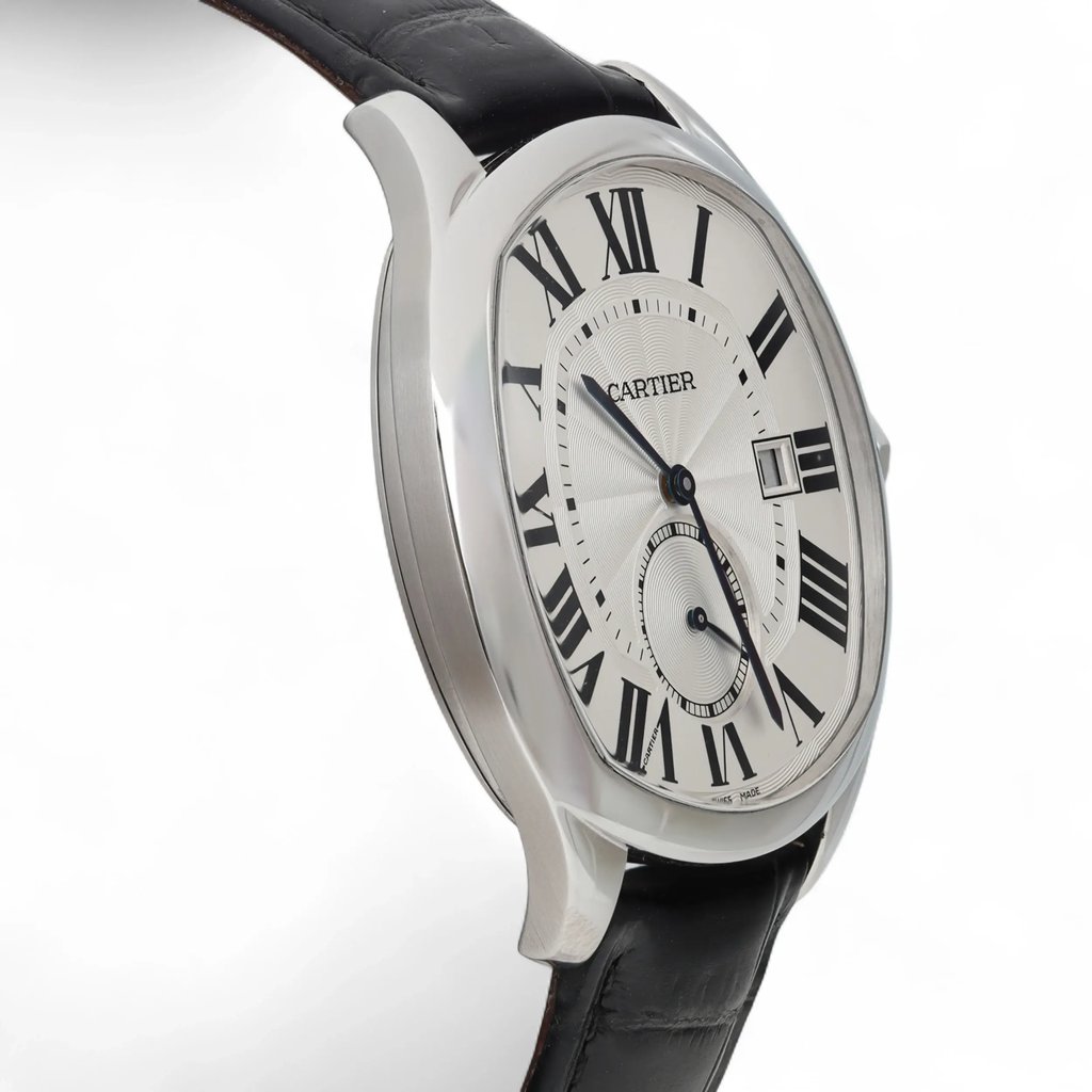 An image of a pre-owned Cartier men's wristwatch, captured from a slightly angled side view. The watch features a stainless steel case with a black leather strap. The dial displays large Roman numerals and a date indicator. The photograph is taken from a close distance, showcasing the watch's elegant design and details.