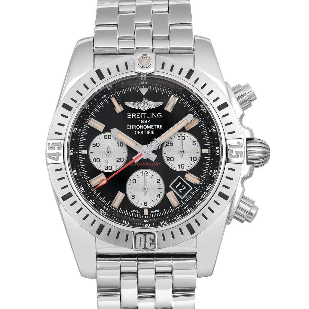 An image of a pre-owned Breitling men's luxury wristwatch, presented in a front close-up shot emphasizing the watch face. The watch is shown at a straight-on angle with the entire watch face and partial bracelet visible in good condition. The round dial is black with beige non-numeric hour marks and stick indexes, featuring three sub-dials and a date window between the 4 and 5 o'clock position. It has a steel-colored unidirectional bezel and a stainless steel band. The photo is taken from a close distance to showcase details like the "BREITLING 1884 CHRONOMÈTRE CERTIFIE" text and the tachymeter scale around the dial's rim. The watch is pre-owned in good condition and shows minor dings visible on the lugs and minor nicks on the back case. 