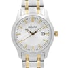 An image of a front close-up shot of a Bulova women's wristwatch, showcasing a round silver sunburst dial with stick indexes and a date indicator at the 3 o'clock position. The watch has luminous hands, a steel bezel, and a two-tone stainless steel band. The watch face is centered and shown in excellent condition, at a distance that allows clear visibility of the brand name and details.