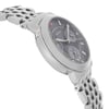 An image of a wristwatch shown from a side profile view, opposite the crown. The angle highlights the watch’s sleek metallic casing and intricate linked bracelet. The watch face displays multiple dials and markers, captured at a slight tilt, providing a detailed view of its design. The photo is taken from a close distance, emphasizing the craftsmanship and condition of this display model.