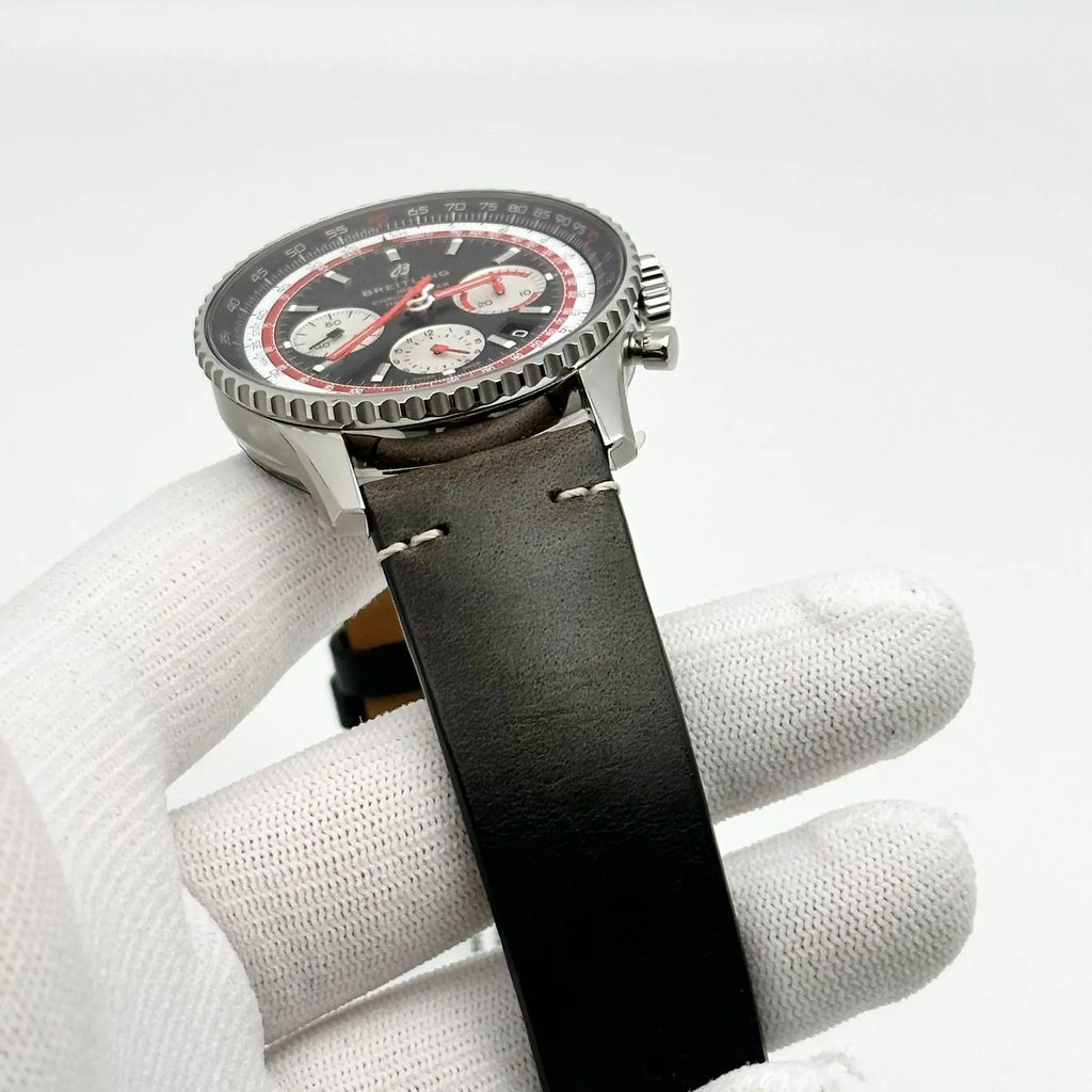 An image of a Breitling men's wristwatch in display model condition, showcased at a side angle with the watch face tilted upwards towards the camera. The watch features a chronograph, date indicator, and luminous hands, along with a small seconds subdial. It is positioned on a white-gloved hand against a white background, allowing clear visibility of the watch details. The black leather band shows discoloration consistent with storage, and the watch is in close-up view, providing a detailed look at the textures and design elements.