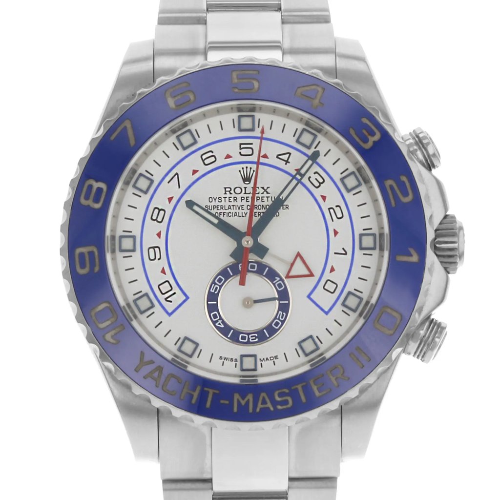 An image of a pre-owned wristwatch showing a front close-up shot of the watch face. The watch features a prominent blue bezel with "Yacht-Master II" inscribed at the bottom. The dial is white with bold, dark hour markers and multiple hands, including a red triangle-tipped hand. The brand name is visible near the top center of the watch face. The image captures the details of the watch from a straight-on angle, highlighting its intricate design elements.