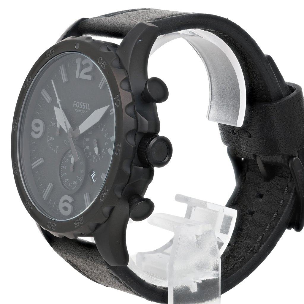 An image of a Fossil wristwatch positioned at a slight angle from the front, showcasing the watch face and side buttons. The watch features a black dial with large numerals and three sub-dials. The black leather strap is visible, with the watch resting on a transparent stand. The photo is taken at a close distance to highlight the details, such as the textured bezel and prominent crown. The watch condition is marked as new with defects.