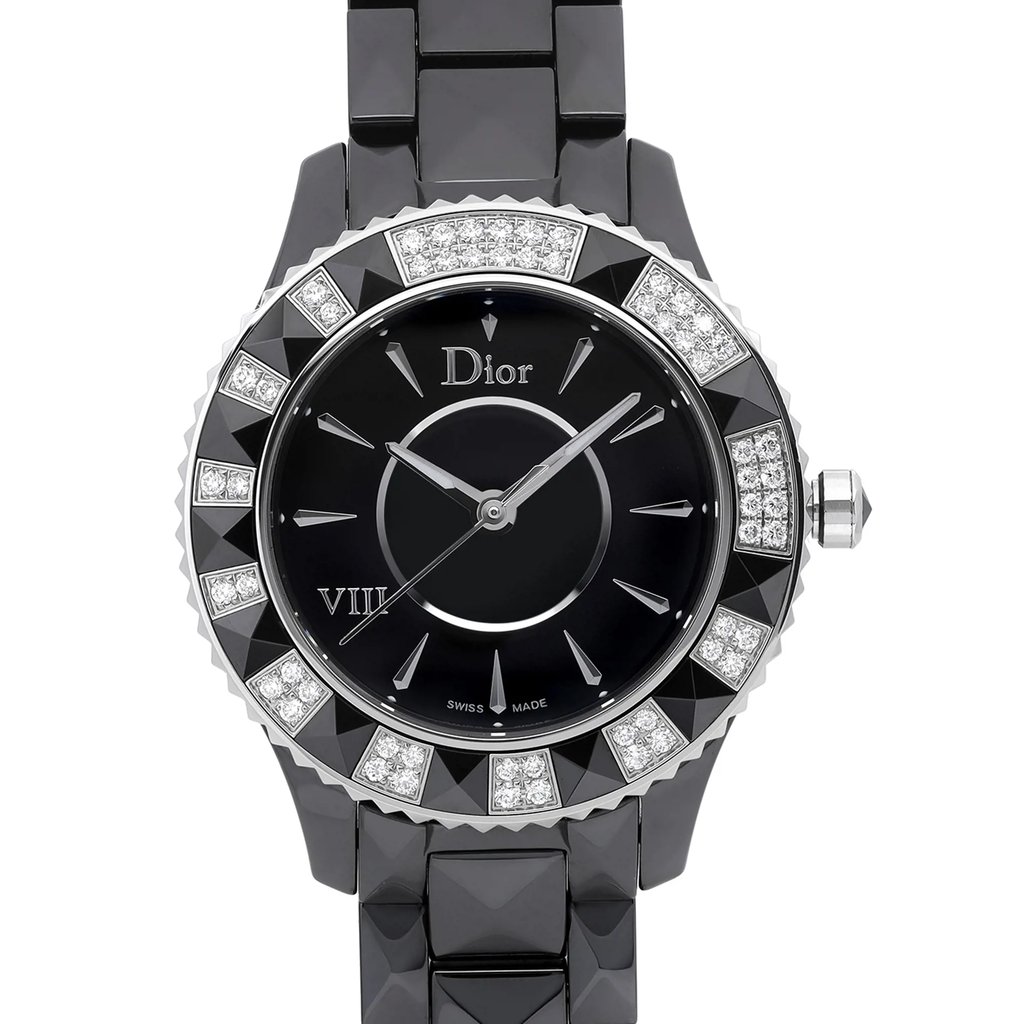 An image of a display model wristwatch captured in a front close-up shot. The watch face is prominently featured, showcasing elegant details and a sophisticated design. The bezel is adorned with alternating sections of diamonds and polished metal, surrounding a sleek black dial with silver-tone hands and hour markers. The watch is set against a glossy black strap, enhancing its luxurious appearance.