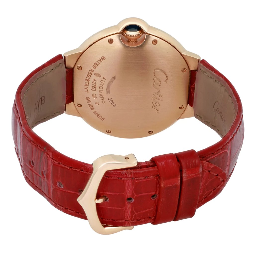 An image of a pre-owned Cartier women's wristwatch viewed from the back at a slight angle, showcasing the gold-toned case and engraved brand details. The watch is positioned slightly to the left, with the focus on the case back and clasp. The red leather strap, featuring a textured pattern, is prominently displayed, with the gold buckle facing the viewer. The watch is photographed at a close distance, highlighting the craftsmanship and design elements.