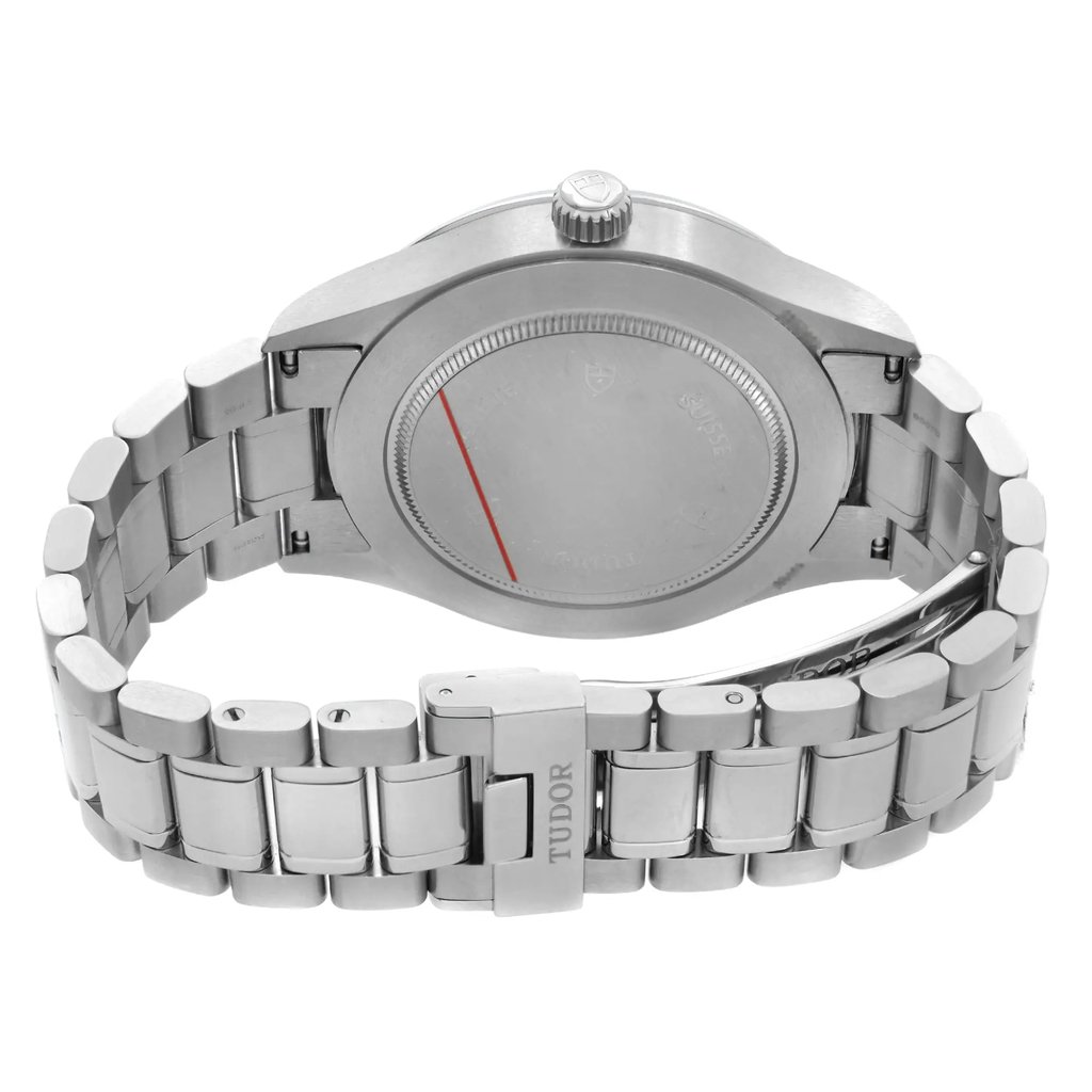 An image of a pre-owned men's Tudor wristwatch, viewed from the back at a slight angle, showcasing the stainless steel bracelet and case. The watch is positioned close-up, highlighting the brand name on the clasp and the detailed engravings on the case back.