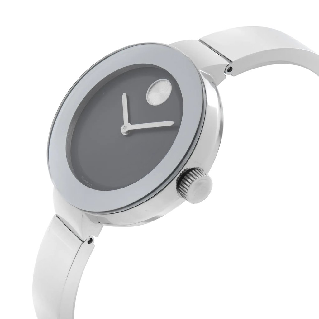 An image of a wristwatch displayed in a side profile view with the crown clearly visible. The watch is positioned at a slight angle, showcasing its sleek design and metallic finish. The focus is on the watch face and band, highlighting the minimalist dial and the polished surface, typical of a display model. The photograph is taken at a close distance, capturing the fine details of the watch's craftsmanship.