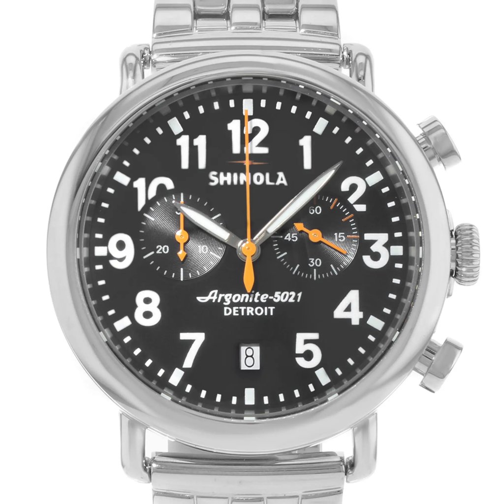 An image of a pre-owned wristwatch taken from a front close-up angle. The watch features a round, black face with large white numerals and two subdials. The hands are orange, contrasting the black background. The case is silver, matching the metal bracelet. The brand name "Shinola" and "Argonite-5021 Detroit" are visible on the watch face.