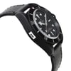 An image of a wristwatch in a side profile view, opposite the crown. The watch displays a black dial with luminous markers and a black bezel, set within a robust case. The angle highlights the watch's thickness and contour, showing the leather strap extending from the case. The watch is a display model, photographed from a close distance, emphasizing the texture and detailing of the materials.