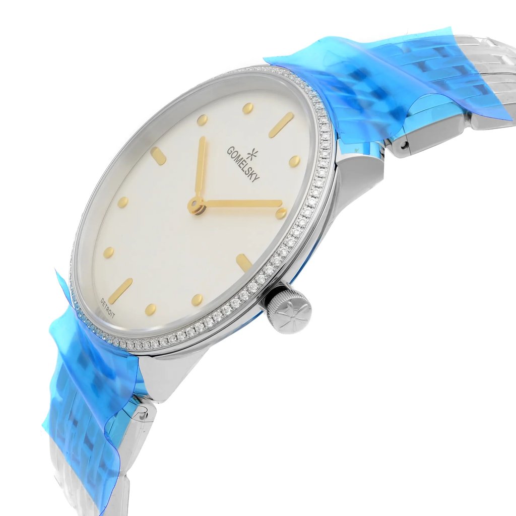 An image of a wristwatch shown from a side profile view, highlighting the crown. The watch features a sleek, unworn design with a silver case and a white dial. It has gold hour markers and hands, with a textured bezel. Blue protective film covers parts of the metal strap, indicating it is new. The angle captures the watch at a slight tilt, focusing on the elegant detailing and craftsmanship.