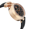 An image of a pre-owned wristwatch captured from the side profile view, opposite the crown. The watch features a rose gold case with a black dial displaying multiple subdials and a date window. The angle of the shot highlights the thickness of the case and the intricate design details. The watch is positioned at a slight angle, with the black textured strap partially visible. The photo is taken from a close distance, emphasizing the craftsmanship and elegance of the timepiece.