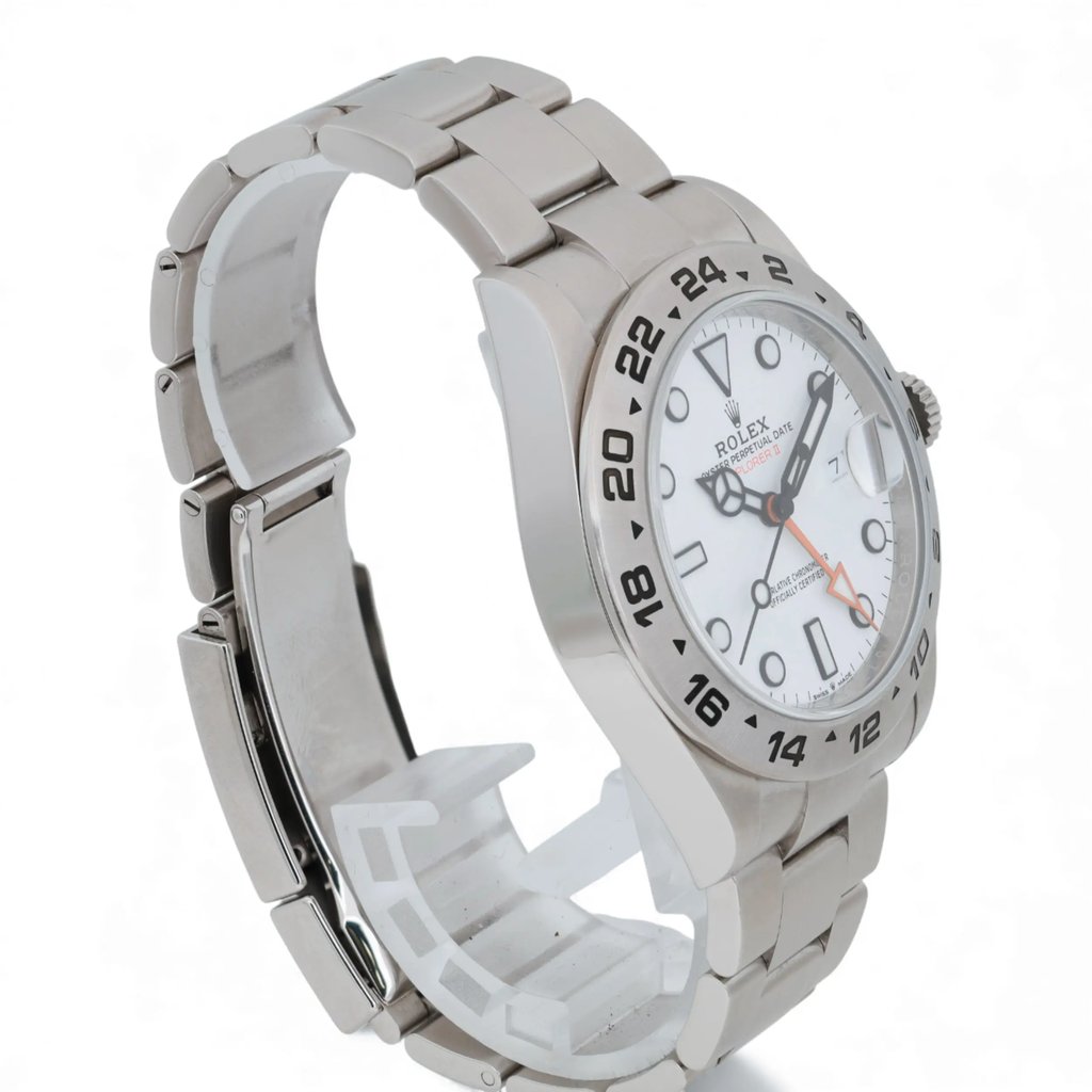 An image of a pre-owned men's Rolex wristwatch positioned at a slight angle, showcasing the right side and face of the watch. The watch features a white dial with a date indicator and luminous hands. The stainless steel bracelet and bezel are clearly visible, with the watch resting on a transparent stand. The image is taken from a medium distance, highlighting the watch's design and details.