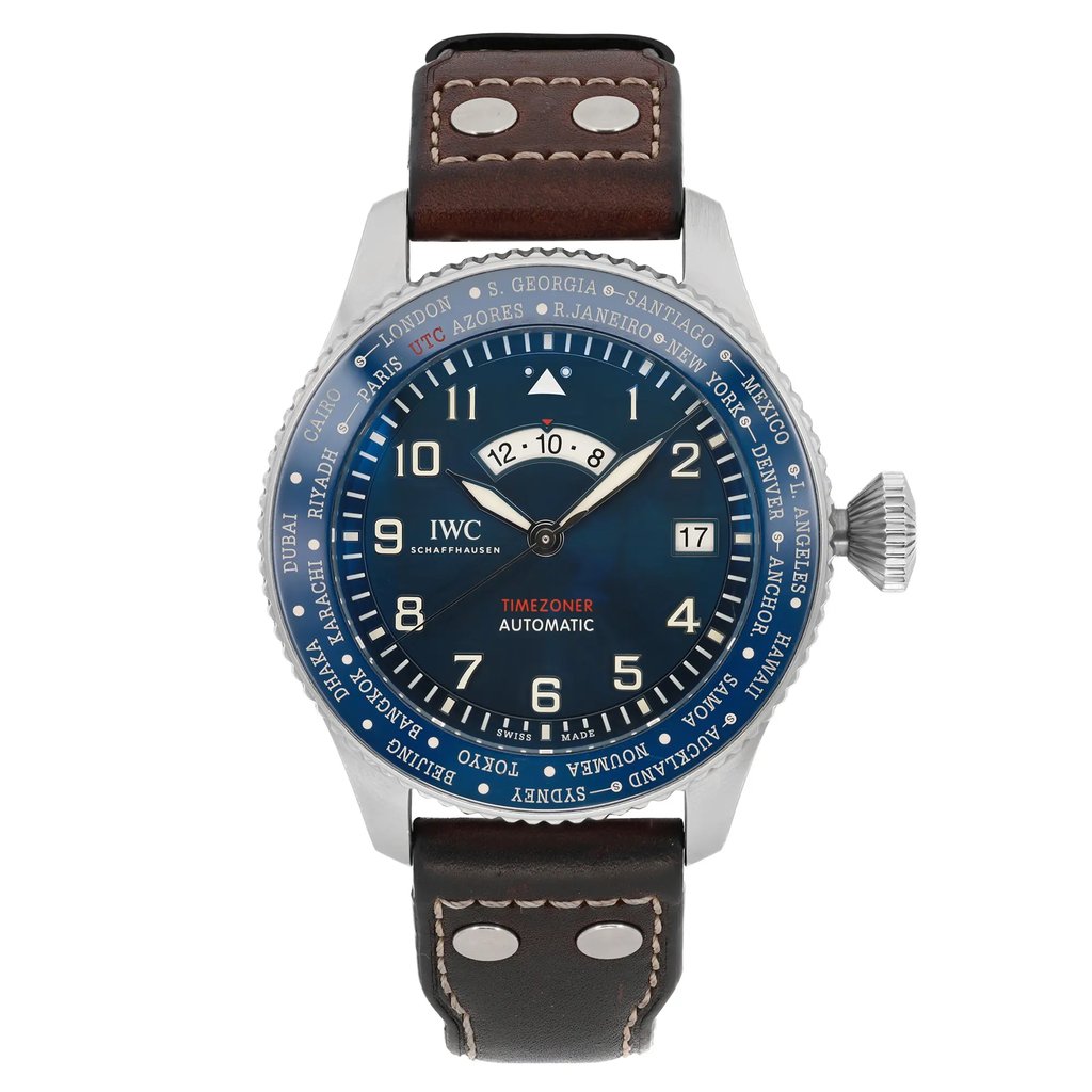 An image of a pre-owned IWC Timezoner Le Petit Prince Edition men's wristwatch positioned upright and facing forward. The watch features a round, blue dial with luminous hands, displaying multiple time zones around the bezel. It has a brown leather strap with visible stitching and metal rivets. The watch is captured at a close-up angle, showcasing the intricate details of its design and functionality.
