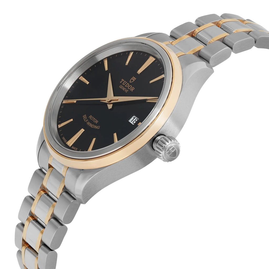 An image of a wristwatch taken from a side profile view, highlighting the crown. The watch is unworn and features a metallic band with gold accents. The black dial is visible with gold hour markers and hands, and there's a date window on the right side. The watch is positioned at a slight angle, providing a clear view of its elegant design and craftsmanship.