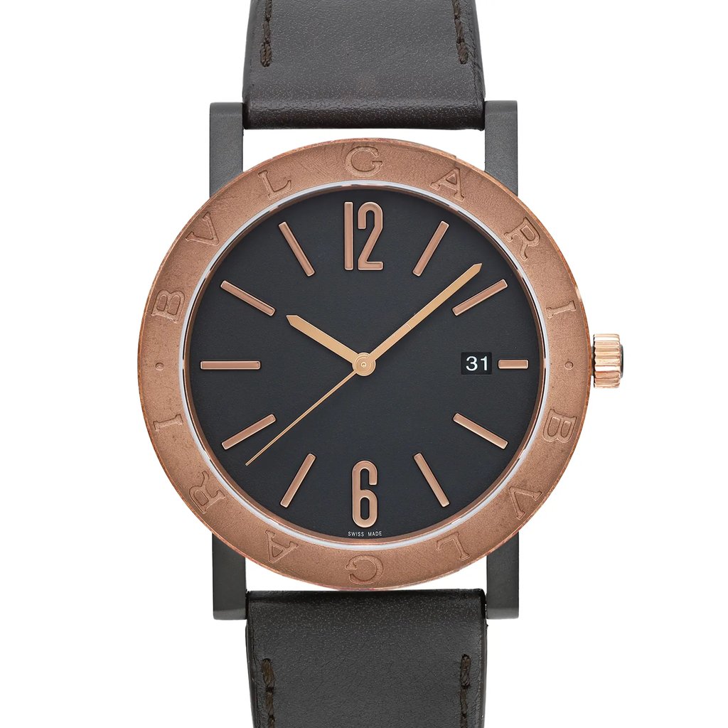 An image of an unworn Bvlgari wristwatch for men in a casual style, featuring a close-up front view of the watch face. The watch has a round stainless steel case with a bronze bezel, black dial, and a leather band. The dial includes stick indexes, a 12-hour display with prominent numbers at 12 and 6, and a date window at the 3 o'clock position. The image is taken from a straight angle at a close distance, focusing on the watch face details.