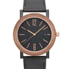 An image of an unworn Bvlgari wristwatch for men in a casual style, featuring a close-up front view of the watch face. The watch has a round stainless steel case with a bronze bezel, black dial, and a leather band. The dial includes stick indexes, a 12-hour display with prominent numbers at 12 and 6, and a date window at the 3 o'clock position. The image is taken from a straight angle at a close distance, focusing on the watch face details.