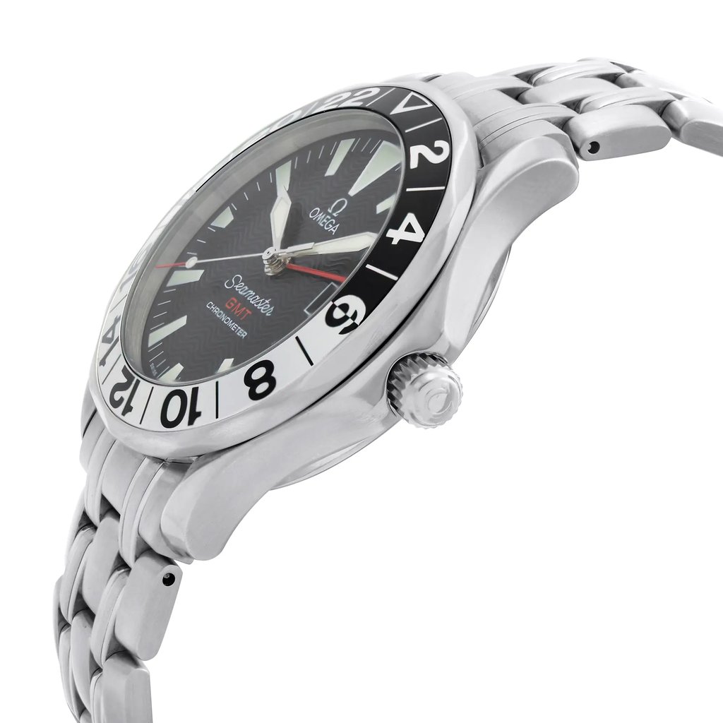 An image of a pre-owned OMEGA men's wristwatch taken from a side angle, showcasing the silver stainless steel case and bracelet. The watch features a black dial with a date indicator, GMT function, and luminous hands. The photograph captures the watch at a slight upward angle, emphasizing the bezel's numerals and the crown's detail. The watch is positioned close-up, highlighting its sleek design and craftsmanship.
