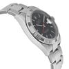 An image of a pre-owned wristwatch viewed from the side profile opposite the crown. The watch features a stainless steel band and a dark dial with white hour markers. The bezel has embossed numbers and the overall angle of the shot showcases the thickness and design of the watch case, highlighting its sleek and polished finish. The photograph is taken at a close distance, offering a detailed view of the watch's craftsmanship.