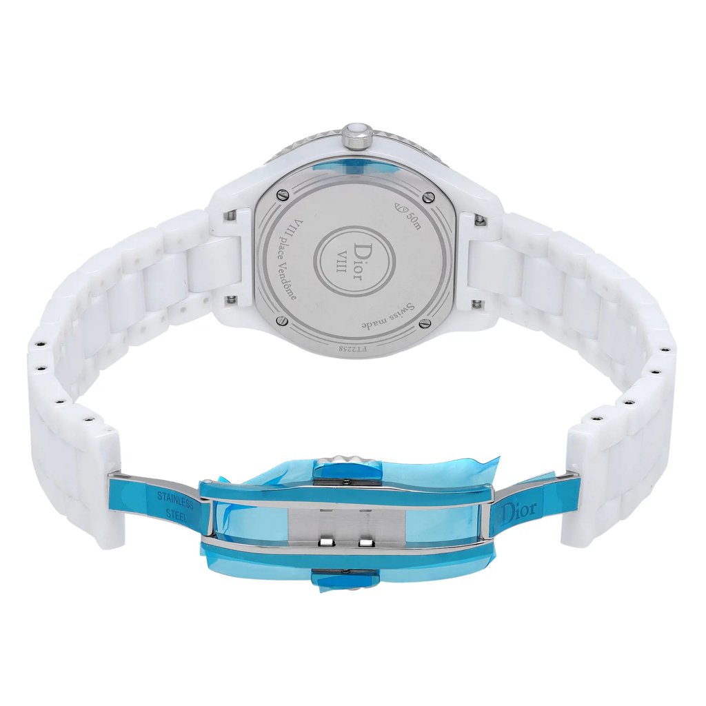 An image of a Dior women's wristwatch displayed from the back view, featuring an open butterfly clasp. The watch has a round ceramic case with a screwback design and a ceramic band. The angle showcases the luminous hands feature indirectly, emphasizing the elegant and sleek design. The image is taken at a close distance to highlight the details and craftsmanship of the display model.