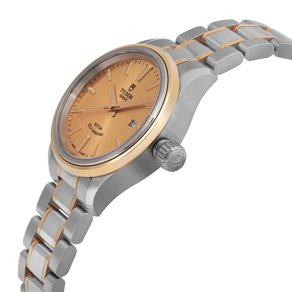 An image of a wristwatch captured from a side profile view, highlighting the crown. The watch features a silver and gold-tone bracelet and a warm, gold-colored face. The crown is prominently visible, showcasing its detailed design. The watch appears unworn, with a pristine and polished finish.