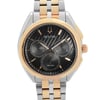 An image of a pre-owned Bulova men's wristwatch in a casual and dress/formal style. The photograph is a front close-up shot of the watch face, showing the watch at a direct angle and close distance to capture detail. It features a black dial with non-numeric hour marks, including multi-dials for the chronograph function, and luminous hands. The round case and band are made of stainless steel with gold accents on the bezel and band. The watch also has a 12-hour dial display.
