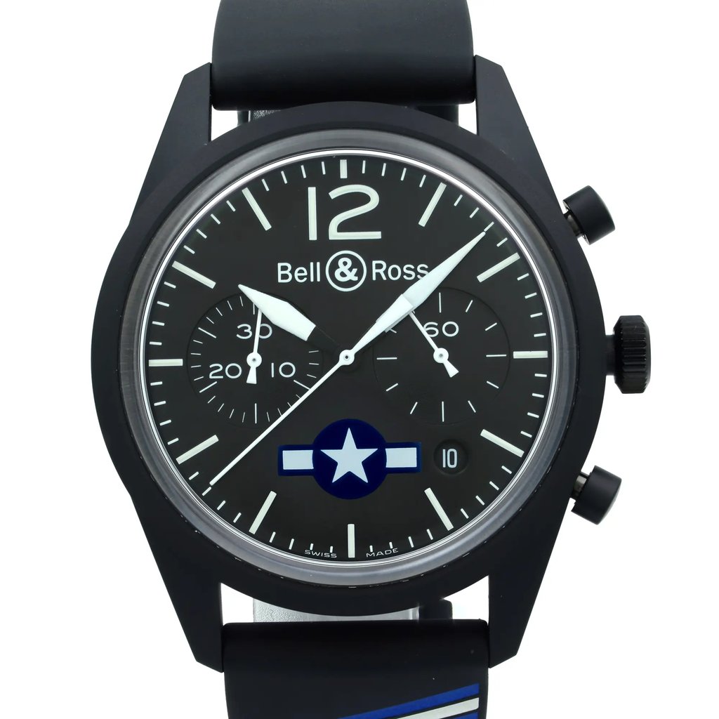 An image of a wristwatch shown in frontal view, positioned centrally and close-up. The watch has a black case and strap, with a black dial featuring white stick indices and the logo "Bell & Ross" at the top right below the 12 hour marker. It has a star insignia above the 6 o'clock position. The strap has a blue stripe detail near the case. Watch condition is unworn