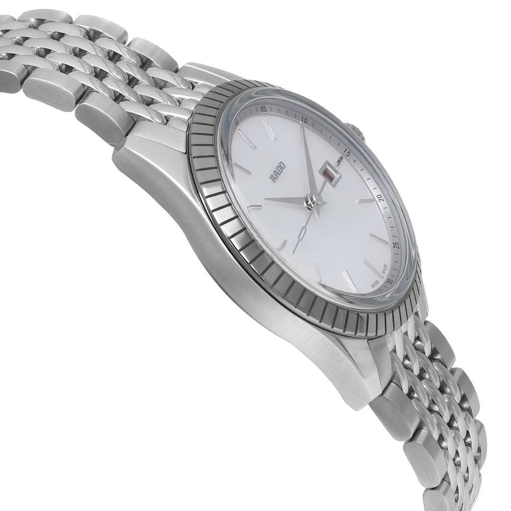 An image of an unworn Rado women's wristwatch presented in a dress/formal style, captured from a side profile view opposite of the crown. The watch features a round stainless steel case and a stainless steel band, with a close-up angle that emphasizes the watch's bezel, which is stainless steel The dial is white with a mother of pearl pattern, and the hands of the watch are clearly visible. The image is taken from a medium distance, showcasing the watch's design and the texture of the stainless steel band.