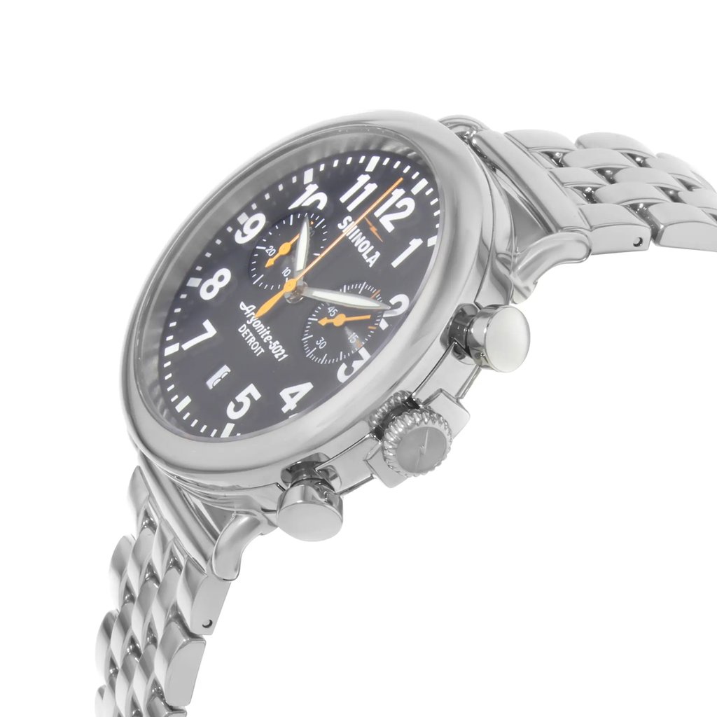 An image of a pre-owned wristwatch captured from a side profile view, highlighting the crown. The watch features a metallic band and a round face with a black dial. Large white numerals and two sub-dials are visible. The angle showcases the watch's thickness and detailing on the side, with the crown prominently displayed. The watch is positioned at a slight angle, providing a clear view of its design elements.