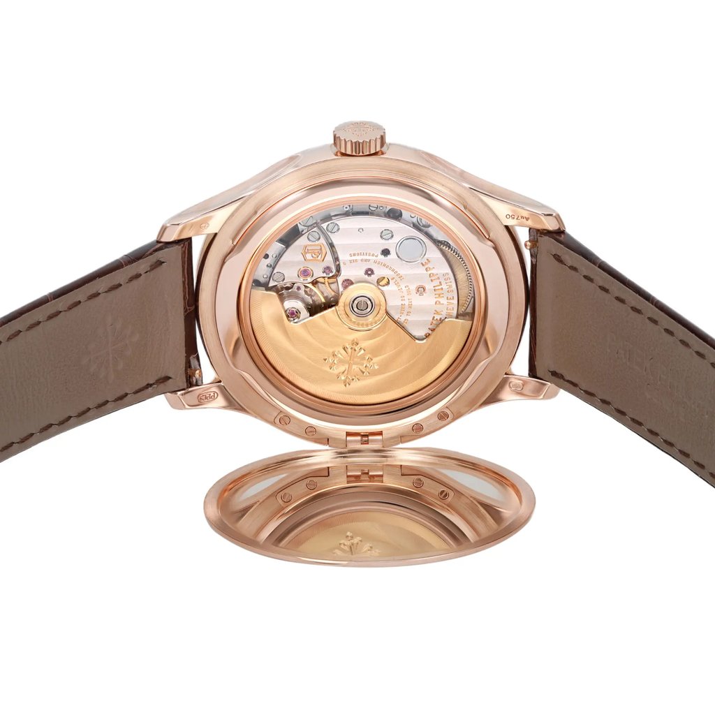 An image of a pre-owned wristwatch shown from the back view. The watch is positioned with an open clasp, allowing a clear view of the intricate mechanical movement inside the case. The watch is angled slightly forward, and the distance is close enough to capture the detailed engravings and components. The leather strap is visible on either side, adding contrast to the metallic finish of the watch case.