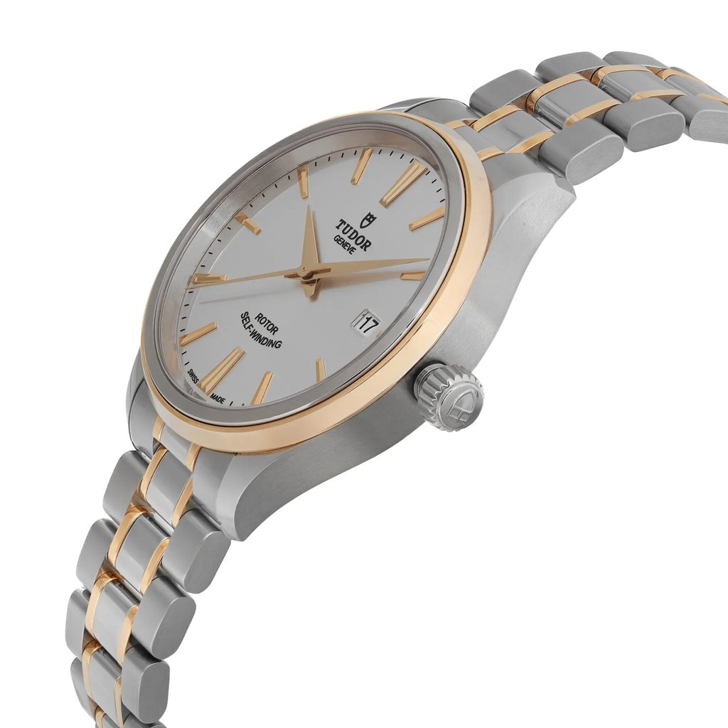 An image of a wristwatch shown from a side profile view, highlighting the crown on the right side. The watch is unworn and features a two-tone metal bracelet with gold accents. The face of the watch is white with gold hour markers and hands, and a date window at the 3 o'clock position. The watch is positioned at a slight angle, capturing both the side and a partial front view.