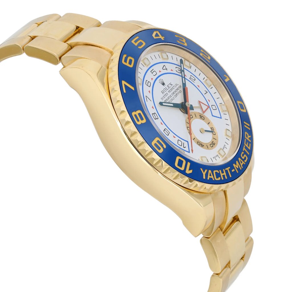 An image of a pre-owned wristwatch viewed from the side profile, opposite the crown. The watch features a gold case and bracelet, with a prominent blue bezel displaying the words "Yacht-Master II." The face of the watch is white with various markings and hands, viewed from a close angle.