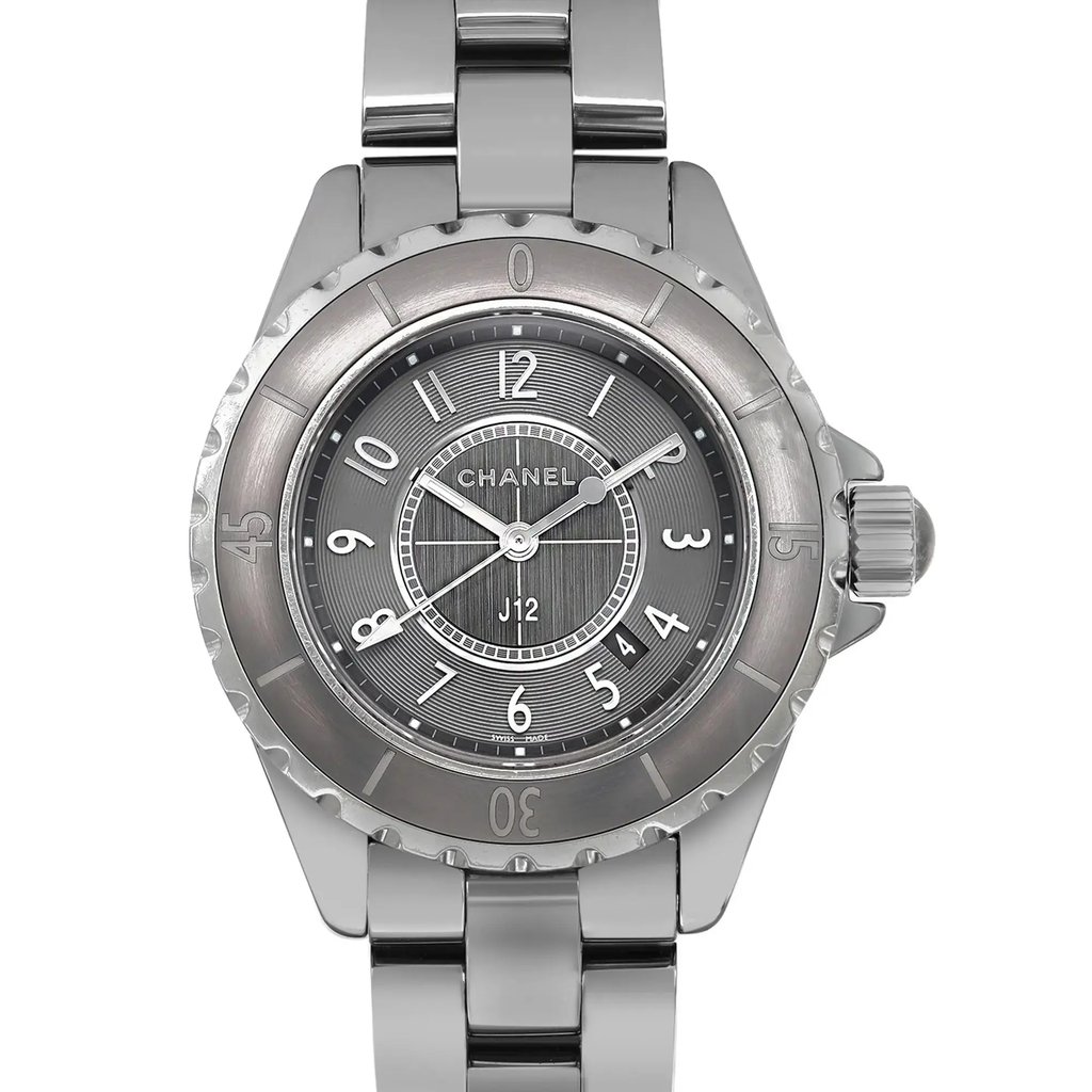 An image of a pre-owned CHANEL wristwatch in good condition, presented in a front close-up view showcasing the round gray dial within a gray ceramic case. The watch features Arabic numerals, a 12-hour dial, a date indicator at the 4.5 o'clock position, and luminous hands. The bezel is marked with minute indices, and the ceramic band displays light scratches and signs of wear. The angle of the shot is head-on, focusing on the face and a portion of the band, with the watch appearing at a close distance for clear detail visibility.