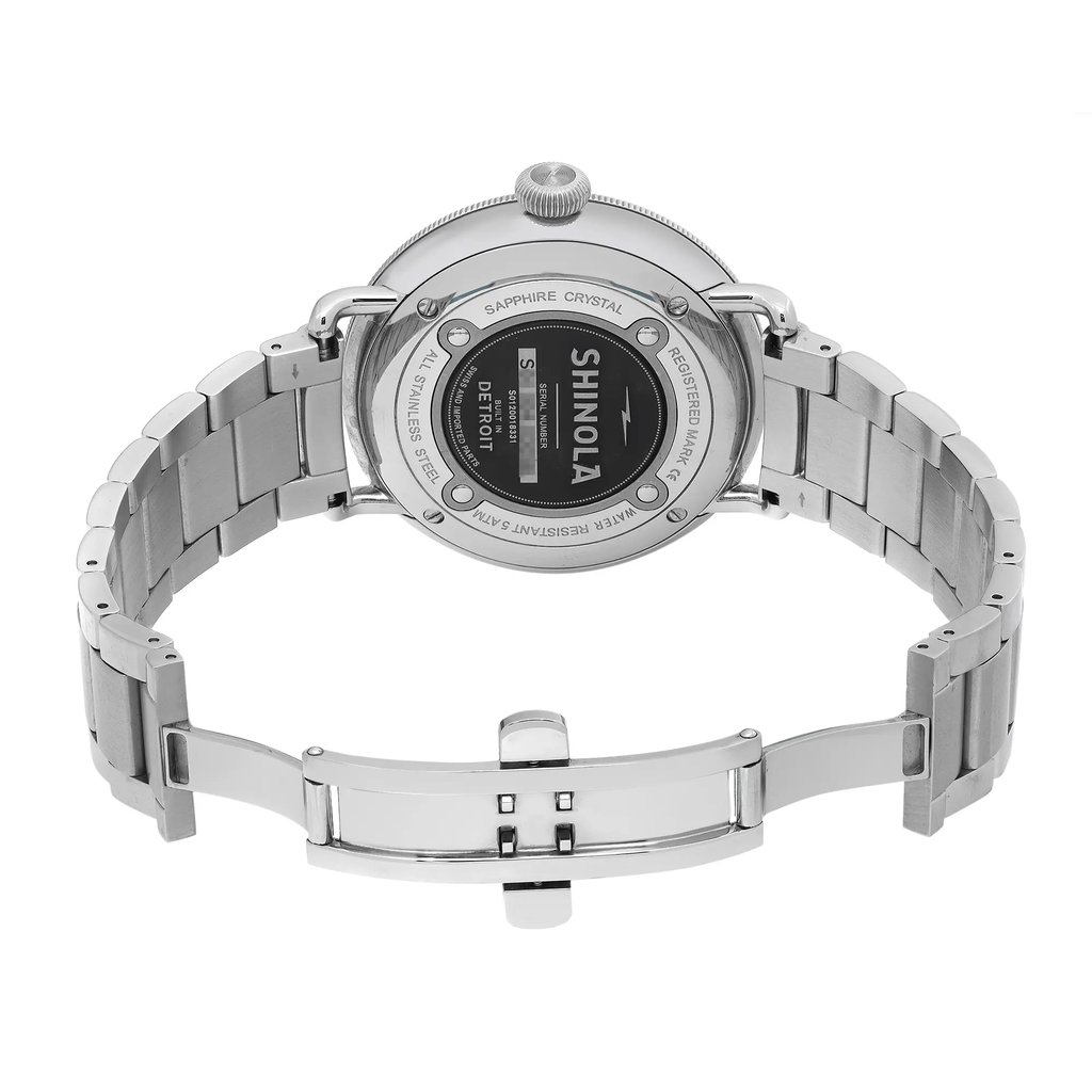 An image of a wristwatch viewed from the back, displaying an open clasp. The watch is a display model with a metallic band, showcasing detailed engravings on the case back. Positioned at a slight upward angle, the watch is captured from a medium distance, highlighting the craftsmanship and design elements.
