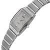 An image of an unworn Rado women's luxury wristwatch in a side profile view with the crown visible, positioned centrally and up-close. The watch has a silver dial and bezel, with a band and case made of white gold. The watch shape is rectangular, and the band features rows of what appear to be diamonds adding to the luxury aesthetic. The Rado logo and brand name are visible on the dial.
