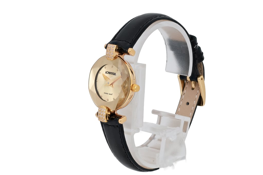 An image of a pre-owned JOWISSA women's wristwatch, positioned at a three-quarter angle from the left side. The watch features a gold-toned, faceted round dial with minimalist hour markers and gold hands. It is set on a black strap with a polished finish, resting on a clear display stand. The image captures the watch from a medium distance, highlighting its elegant design and detailing.
