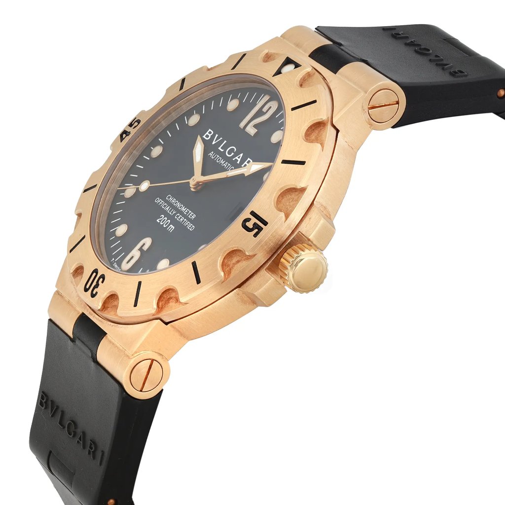 An image of a pre-owned Bvlgari men's wristwatch in a luxury style, showcasing a side profile view with the crown visible. The watch has a round shape with a black dial and gold bezel. yellow gold case and black rubber band, and the band is black with 'BVLGARI' branding. The angle of the photo is a close-up, focusing on the watch's side and partially on the dial, highlighting the contrast between the black strap and the gold case. The band shows signs of wear and light scratches on the watch.