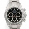 An image of a pre-owned men's Rolex wristwatch, captured from a straight-on angle, displaying the full face and part of the bracelet. The watch features a black dial with luminous hands, a chronograph, and three subdials, including a small seconds subdial. The silver bezel is engraved with a tachymetric scale. The watch is positioned centrally in the frame, filling most of the image space, providing a clear and detailed view.