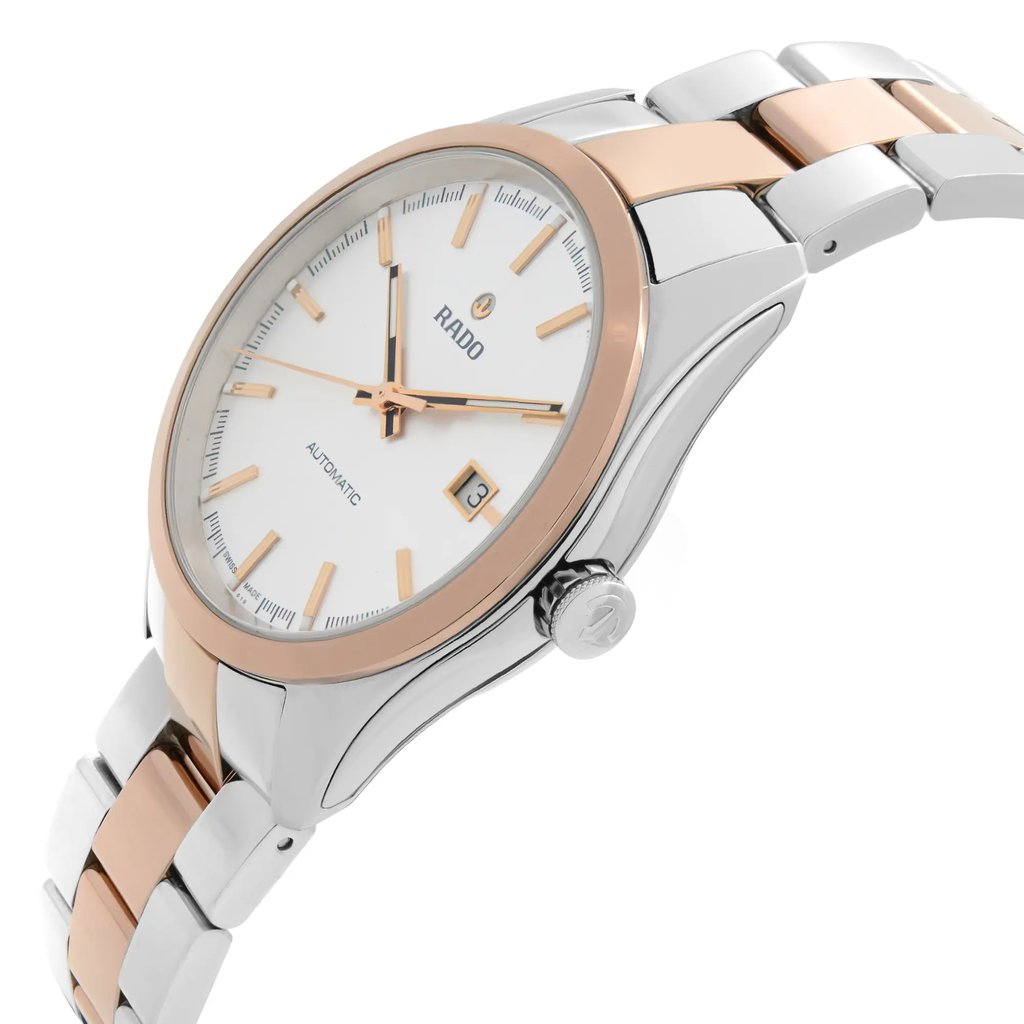 An image of a wristwatch viewed from the side profile, highlighting the crown on the right. The watch features a silver and rose gold-tone metal bracelet and a white dial with gold hour markers. The angle emphasizes the sleek design and polished finish, capturing the watch as a display model.