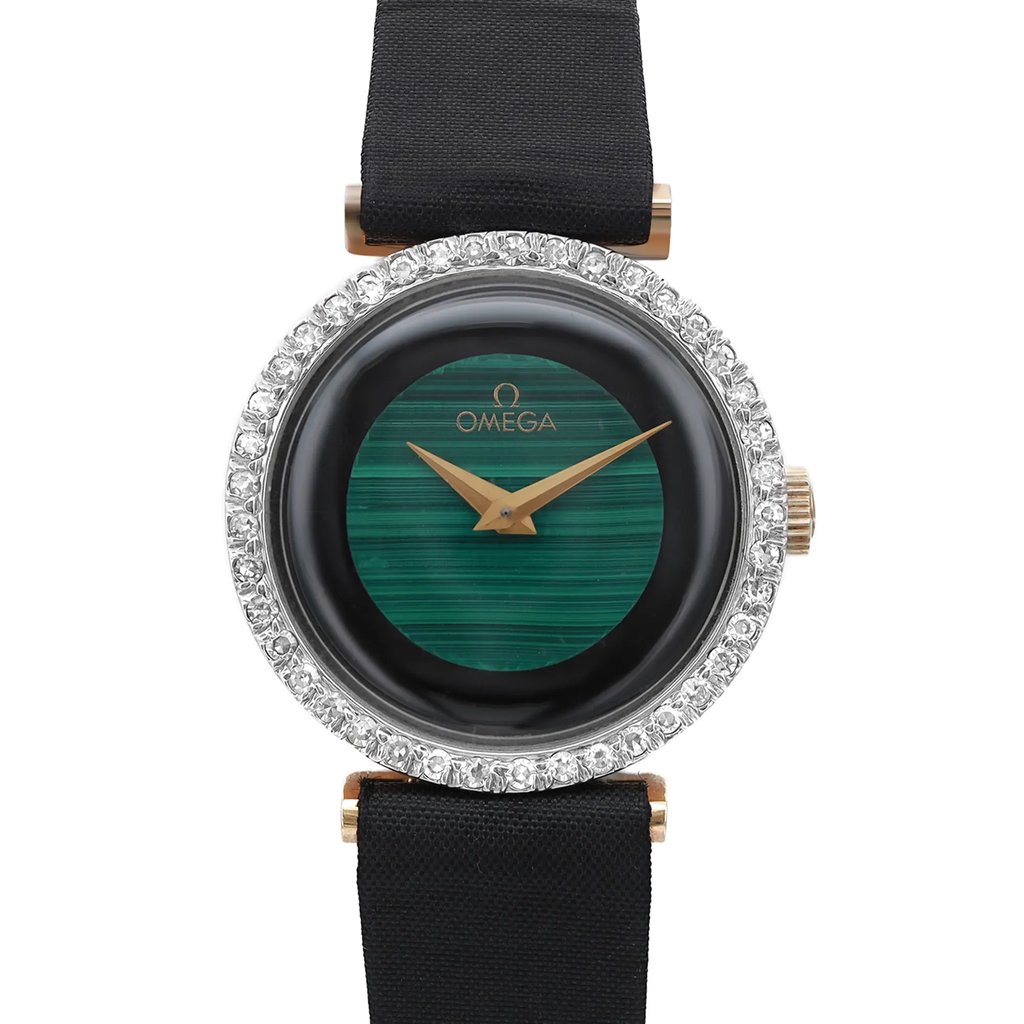 An image of a pre-owned wristwatch positioned front and center, showing a close-up of the watch face. The watch features a green dial with gold hands and is surrounded by a sparkling bezel. The strap is black, providing a contrast to the ornate face. The brand name is visible on the dial.