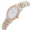 An image of a pre-owned wristwatch viewed from a side profile angle, showcasing the crown prominently. The watch features a two-tone metal bracelet with gold and silver links and a round face with minimalist markers. The distance is close, highlighting the design details.