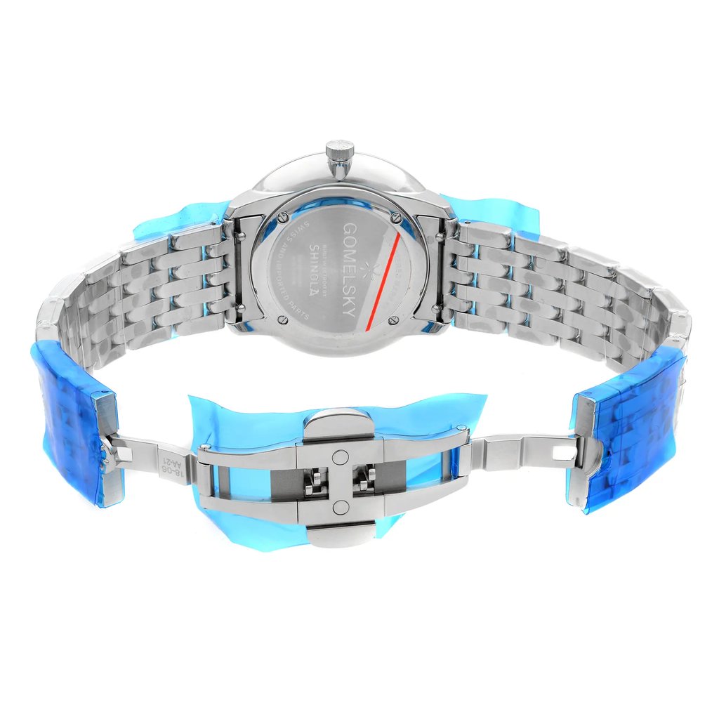 An image of a wristwatch showing the back view with the clasp open. The watch features a metal link band, partially covered with a blue protective film. The back of the watch case displays engraved text. The watch is positioned upright and photographed at close range, clearly highlighting the details of the clasp mechanism and the smooth, unworn condition of the metal surfaces.