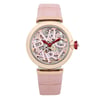 An image of a pre-owned wristwatch displayed from a front full frontal view. The watch features a pink strap with a rose gold bezel. The dial showcases intricate mechanical details and the brand name in stylized lettering. The crown is adorned with a decorative element, adding to the watch's elegant design.