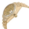 An image of a pre-owned Rolex men's wristwatch, showcasing a side profile view with the crown visible. The watch features a luxurious design with a round shape, gold sunburst dial, day/date function, and luminous hands. It has a yellow gold case and band, with the bezel also in gold. The piece is captured from a close distance, highlighting the details of the watch's side and texture of the band.