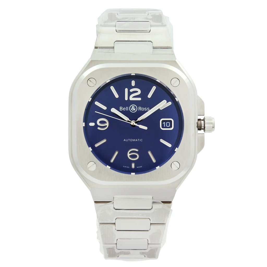 An image of a men's Bell & Ross wristwatch in a display model condition, shown in a full frontal view. The watch has a luxurious and formal style with a cushion-shaped stainless steel case and band. It features a blue dial with white Arabic numerals at 12, 6, and 9 o'clock positions, alongside non-numeric hour marks for the other indices. The hands of the watch are visible and pointing slightly towards the 10 and 2 o'clock positions, suggesting the time is approximately ten past ten. There is also a date display at the 3 o'clock position. The watch is positioned directly facing the camera, with equal distance from all sides, providing a clear and symmetrical view of its features. This watch was never worn.