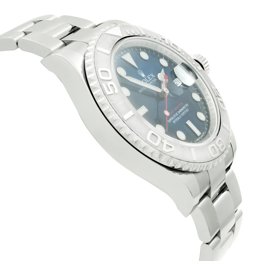 An image of a pre-owned wristwatch viewed from a side profile angle, opposite the crown. The watch has a metallic band and a detailed bezel with engraved numerals. The face of the watch is partially visible, displaying a dark dial with prominent markers. The image is taken at a close distance, highlighting the watch's polished finish and craftsmanship.