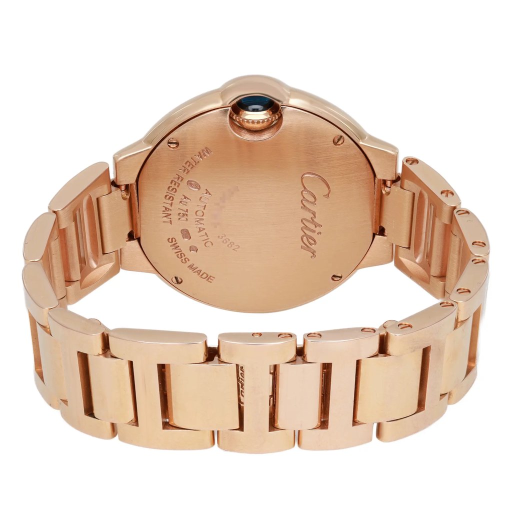 An image of a pre-owned wristwatch shown from the back view with an open clasp. The watch is positioned centrally, with the camera capturing it at a slightly elevated angle to highlight the details on the back case. The focus is on the engraved text and the intricate design of the bracelet links.