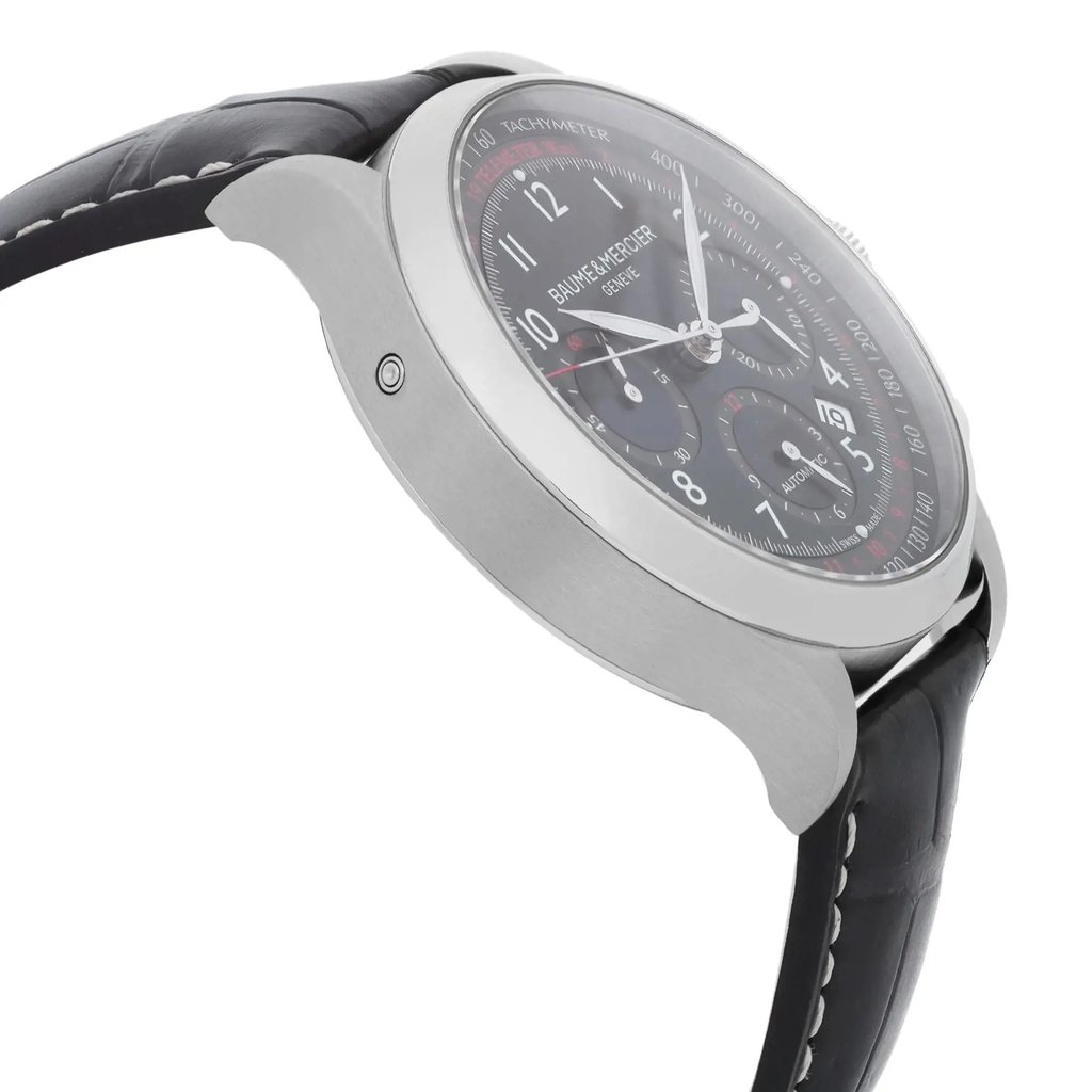 An image of a Wristwatch by Baume & Mercier. This Pre Owned item is designed for Men, featuring a Luxury style. It has a Mechanical (Automatic) movement and an Analog display with a Black dial color. The indices include 12-Hour Dial,Arabic Numerals,Multi Dial. The band is made of Leather and the case is made of Stainless Steel. The watch has a Round shape with a case size of 42 mm and a case thickness of 15 mm.