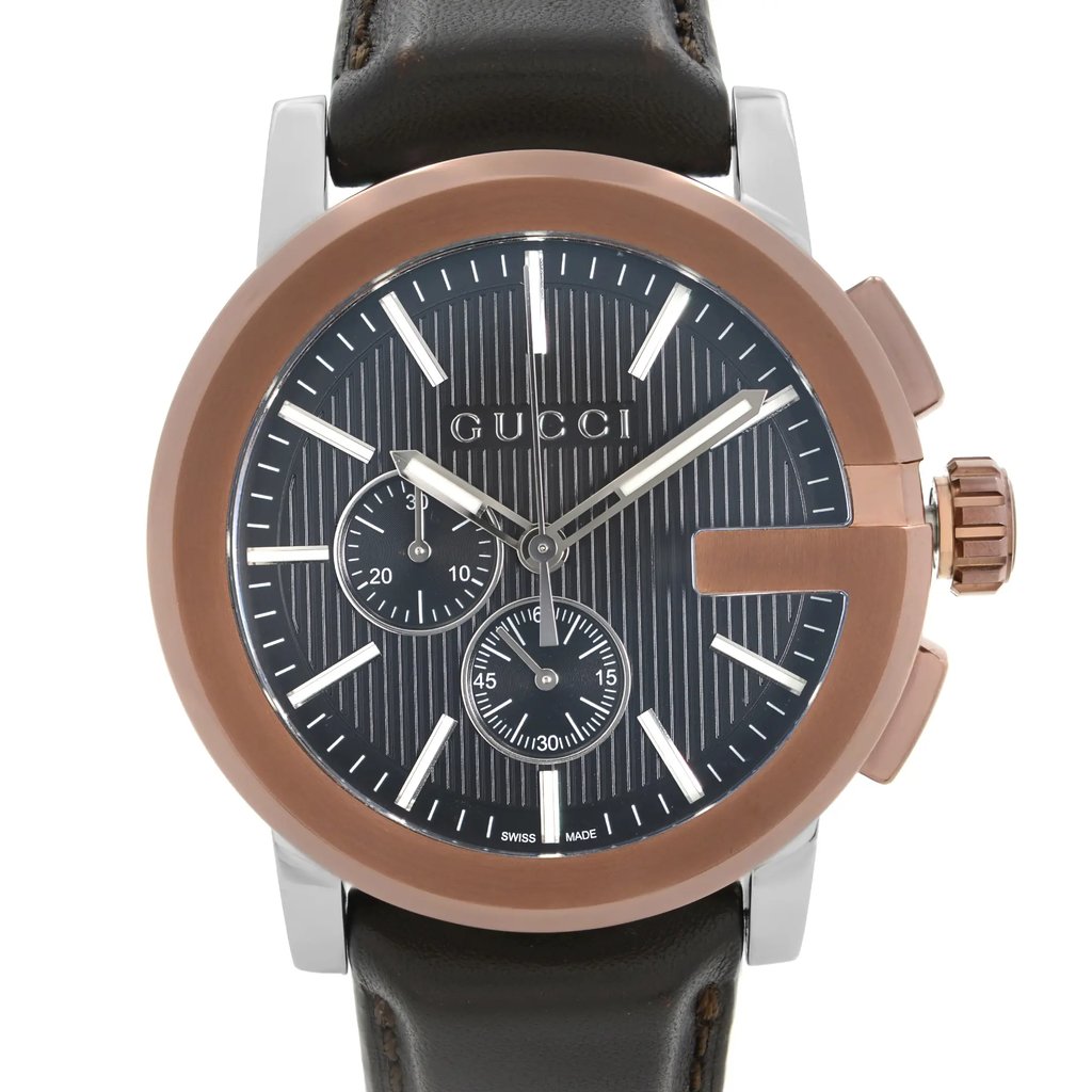 An image of a new Gucci men's dress wristwatch with defects, shown in a front close-up view focusing on the watch face. The watch features a round stainless steel case with a bronze bezel, a black teaked dial, and luminous hands. It includes a chronograph, small seconds subdial, and stick indexes for the 12-hour dial. The band is made of leather. The watch is positioned straight on at a close distance, allowing for clear visibility of details and the Gucci brand name on the dial.